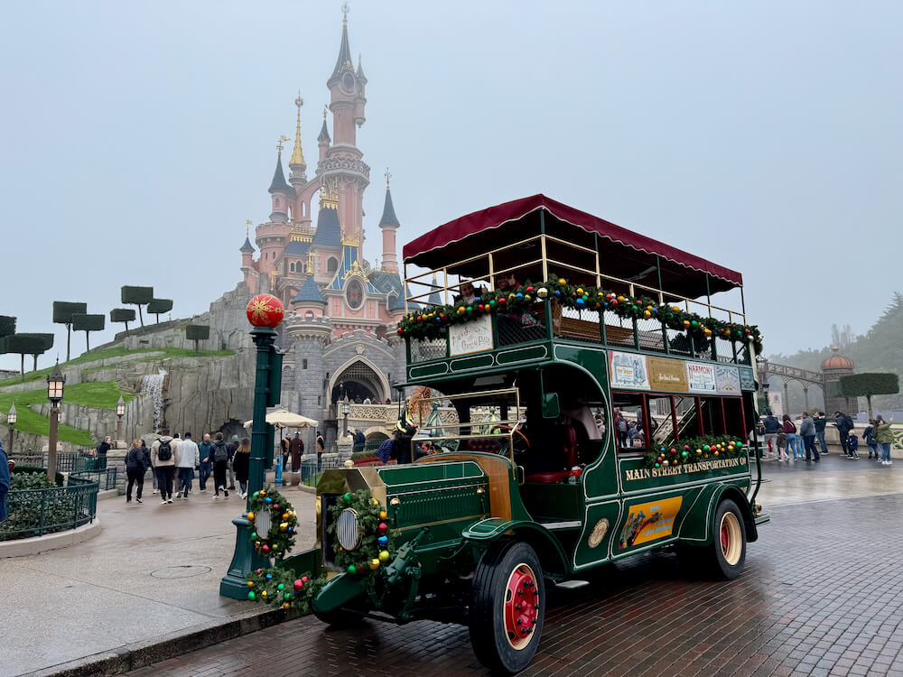 Autobús de Main Street con el castillo de Disneyland Paris decorado de navidad